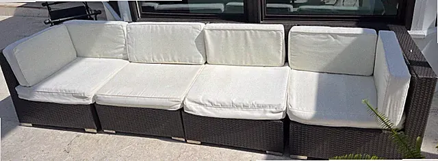 Black Rattan Outdoor Sectional Sofa Set with White Cushions and Armrests.