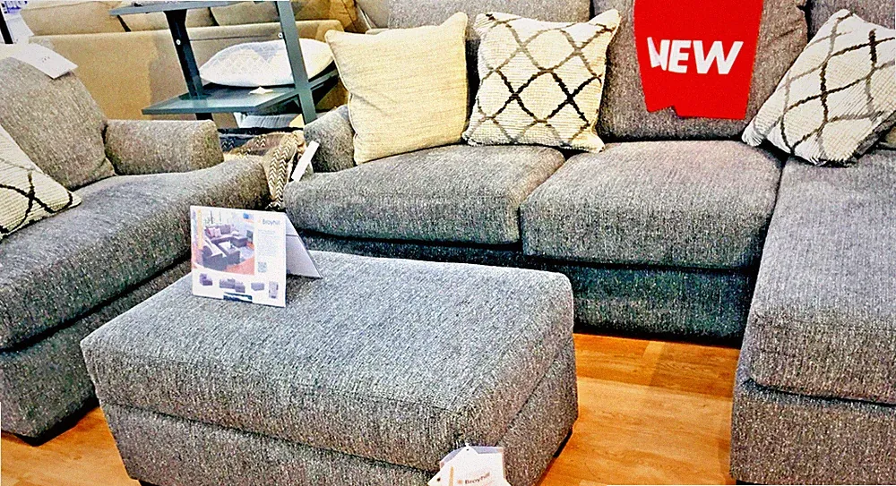 Broyhill gray charcoal fabric chaise sectional sofa with an ottoman.